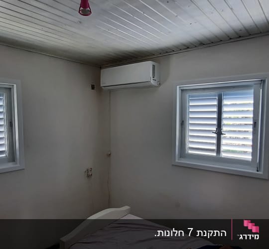 שני חלונות אלומיניום לבנים עם תריסים מותקנים בחדר שינה